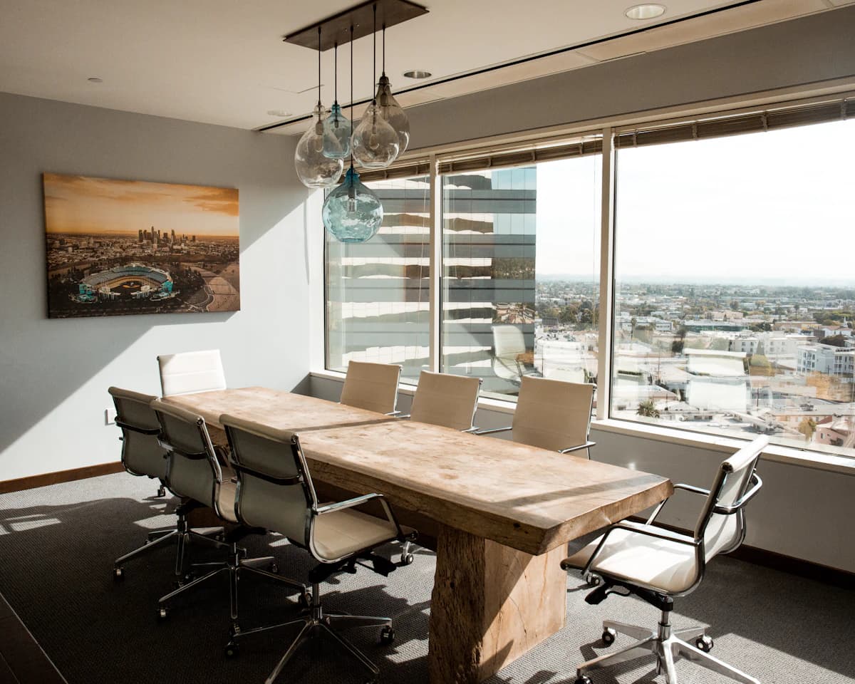 Una sala de juntas refinada con mesa de madera maciza y vista a la ciudad, donde se delega la carga de la nómina.