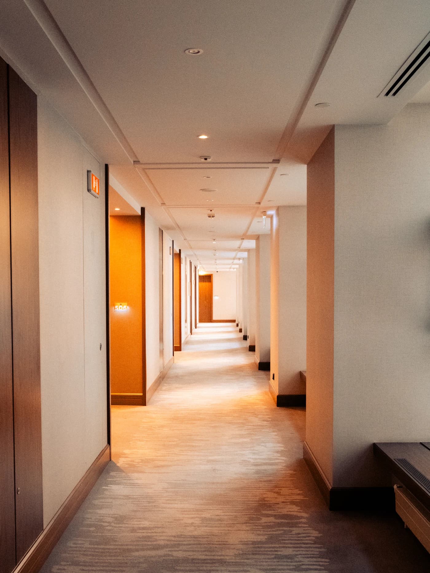 Un pasillo largo de luz cálida con una hilera de puertas idénticas, metáfora visual de la elección entre tres estructuras.